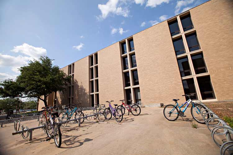 Side exterior view of Lechner Hall, multiple bicycle racks are pictured outside