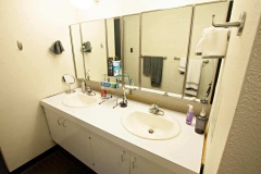 Interior of Aston dorm bathroom, the sink mirror, and cabinets are shown.
