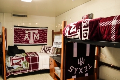 Interior of a Dunn Hall dorm with two beds. One lofted, the other unlocked. The room is decorated with maroon Texas A&M decor.