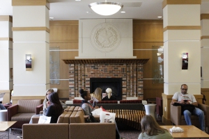 Many students sitting in the Hullabaloo lounge area, in front of the fire place
