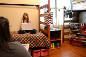 Two students sitting on the beds in their dorms, studying on their laptops.