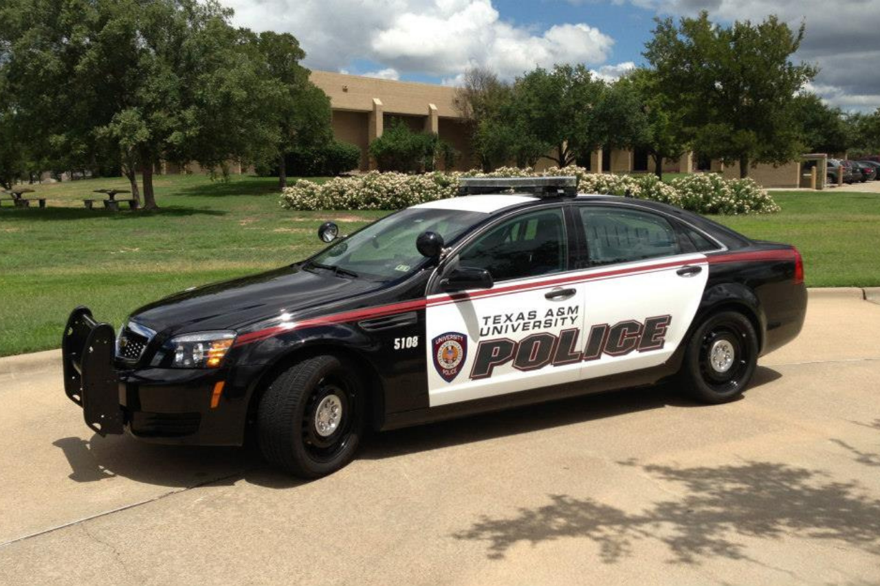 Photo of a Texas A&M University Police Car parked outside, in front of a dorm.