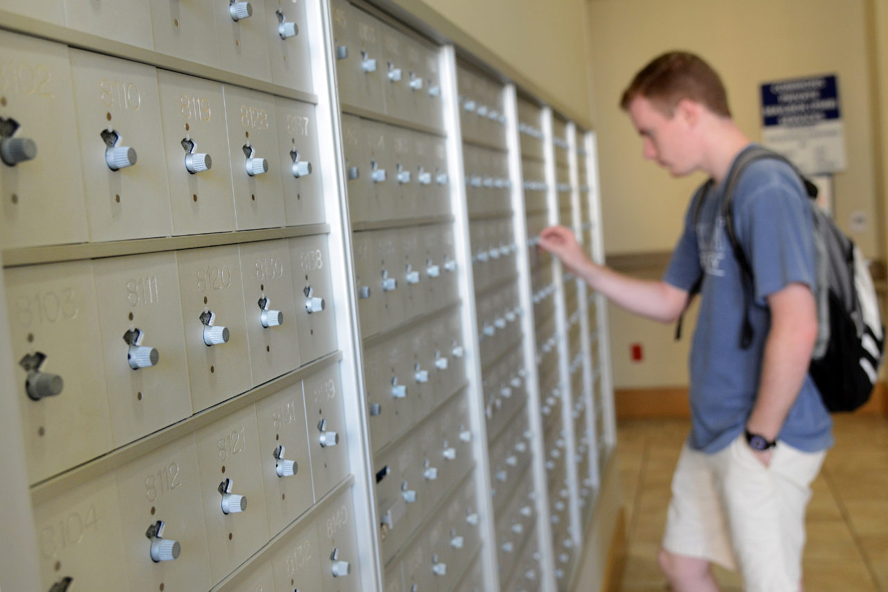 A blurry photo of a male resident checking their mail at the residence hall mailboxes