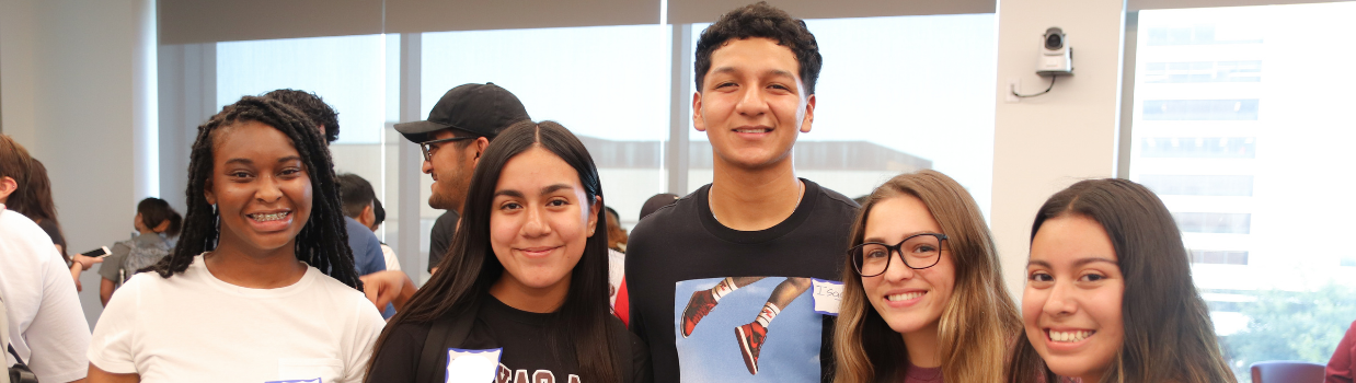 Five students, smiling at the camera at a first generation campus event.