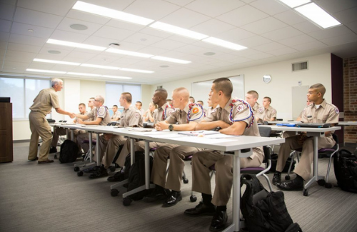 Corps Cadet Instructor lecturing a full class of male cadets in a classroom.