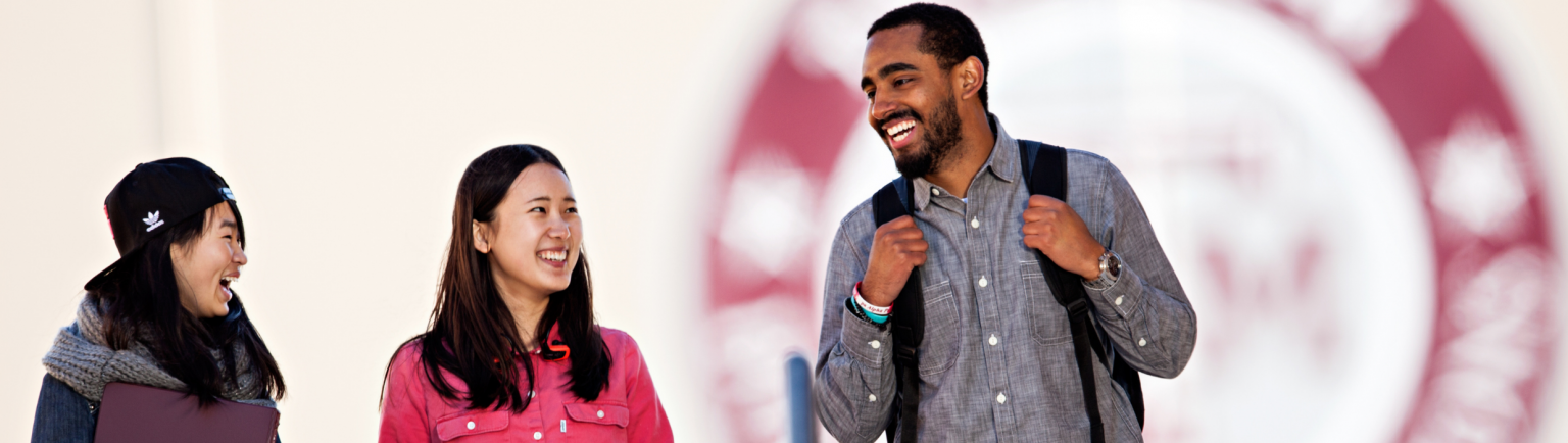 three students smiling and walking on Texas a&m campus together